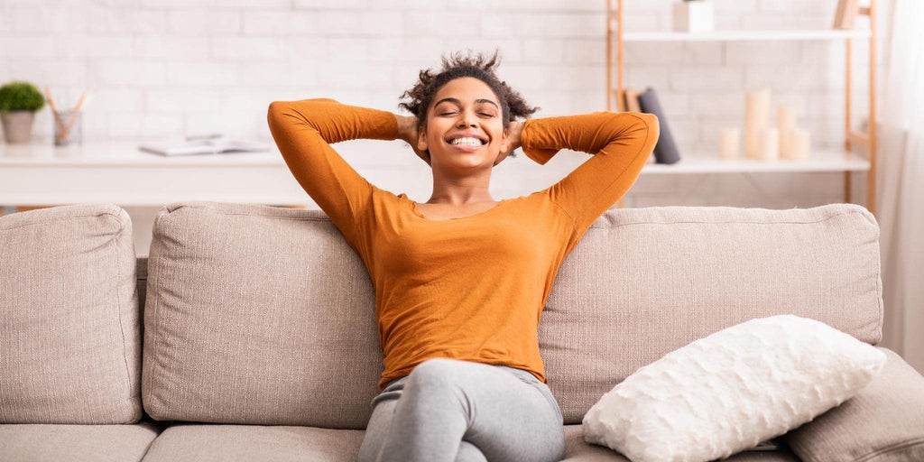 Girl on sofa wearing an orange shirt happy and relaxed sofa by furniturestop.co.uk